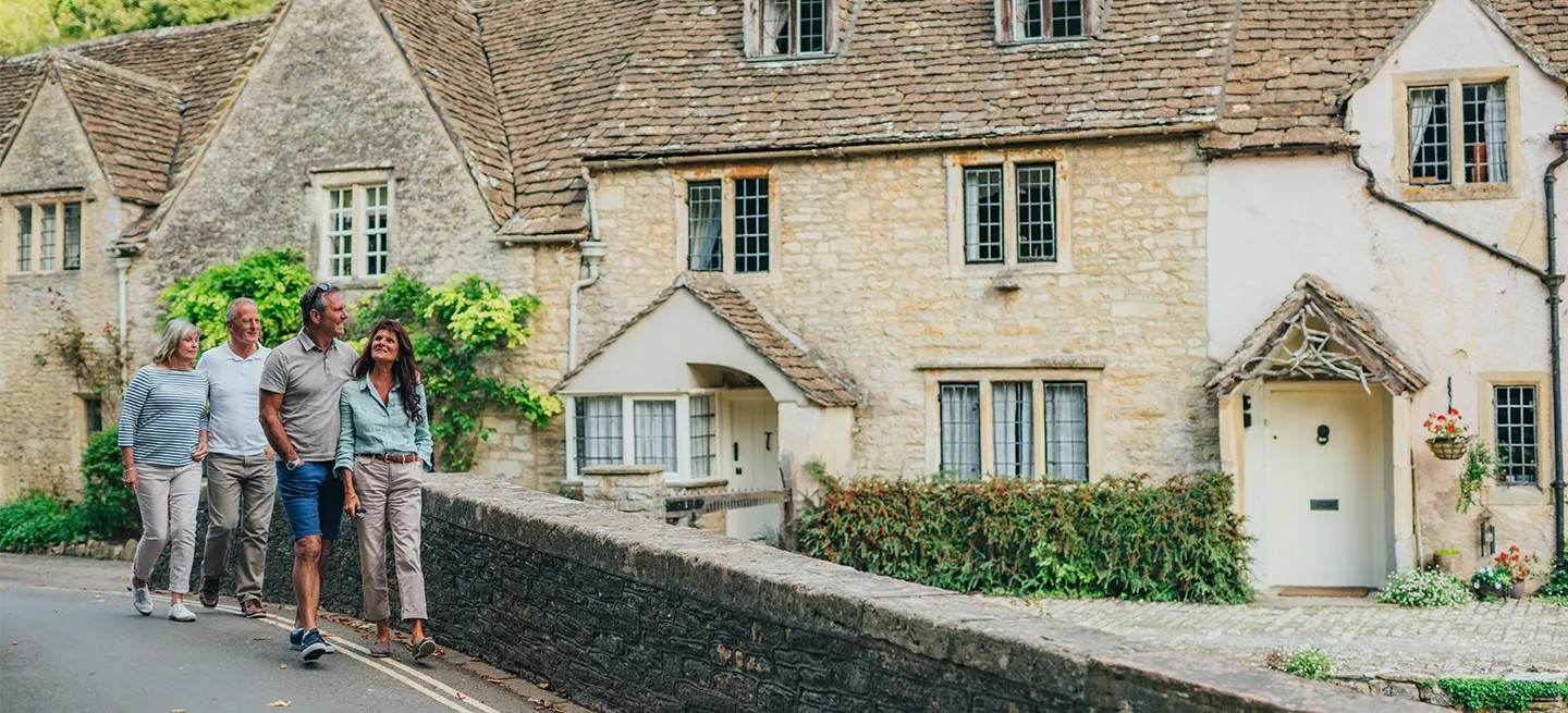 A group of guests walking past stone houses in a traditional village in France.