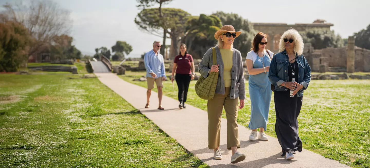 A group of guests walking on a paved path in an archaeological park in Italy.
