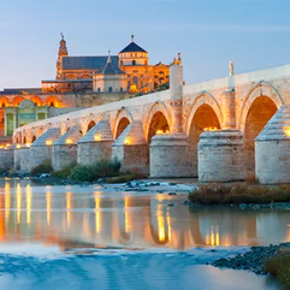 A view of roman bridge and Mosque-Cathedral of Córdoba, Spain, at dusk.